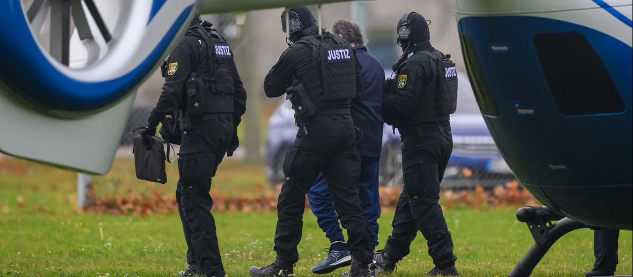 Taleb A. wird von Justizbeamten in der Nähe eines Hubschrauber geführt.
