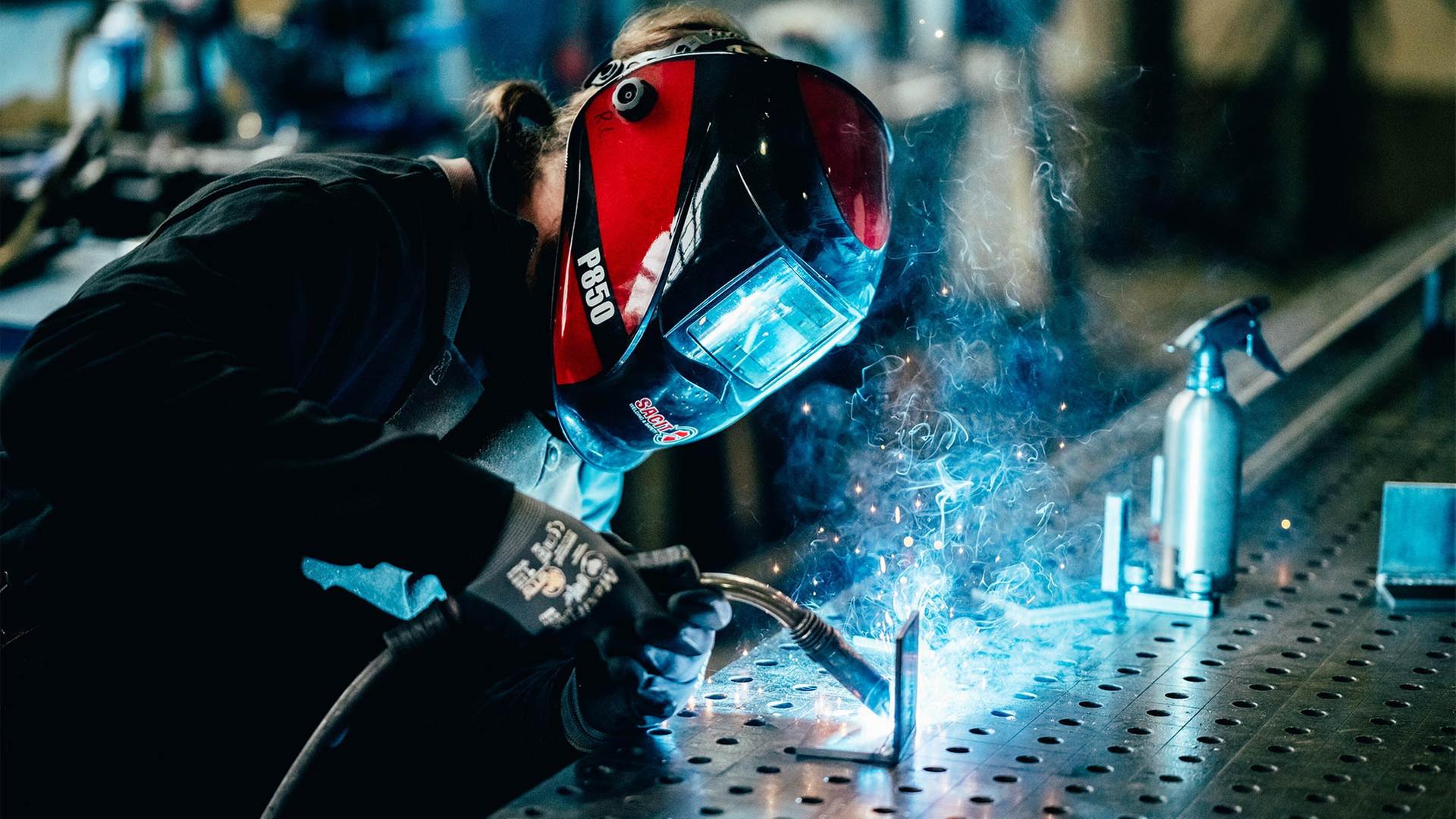Eine Person im Schutzanzug beim Schweißen von Metall. | picture alliance / W2Art / Thors