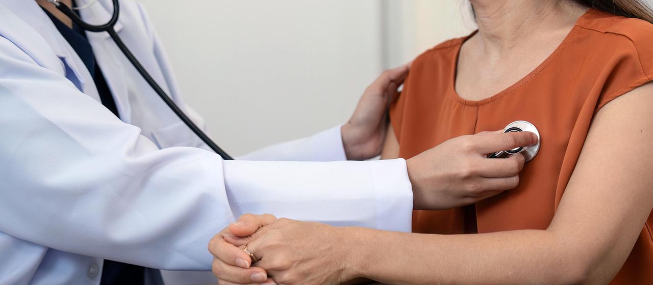 Das Herz einer Frau wird mit einem Stethoskop abgehört