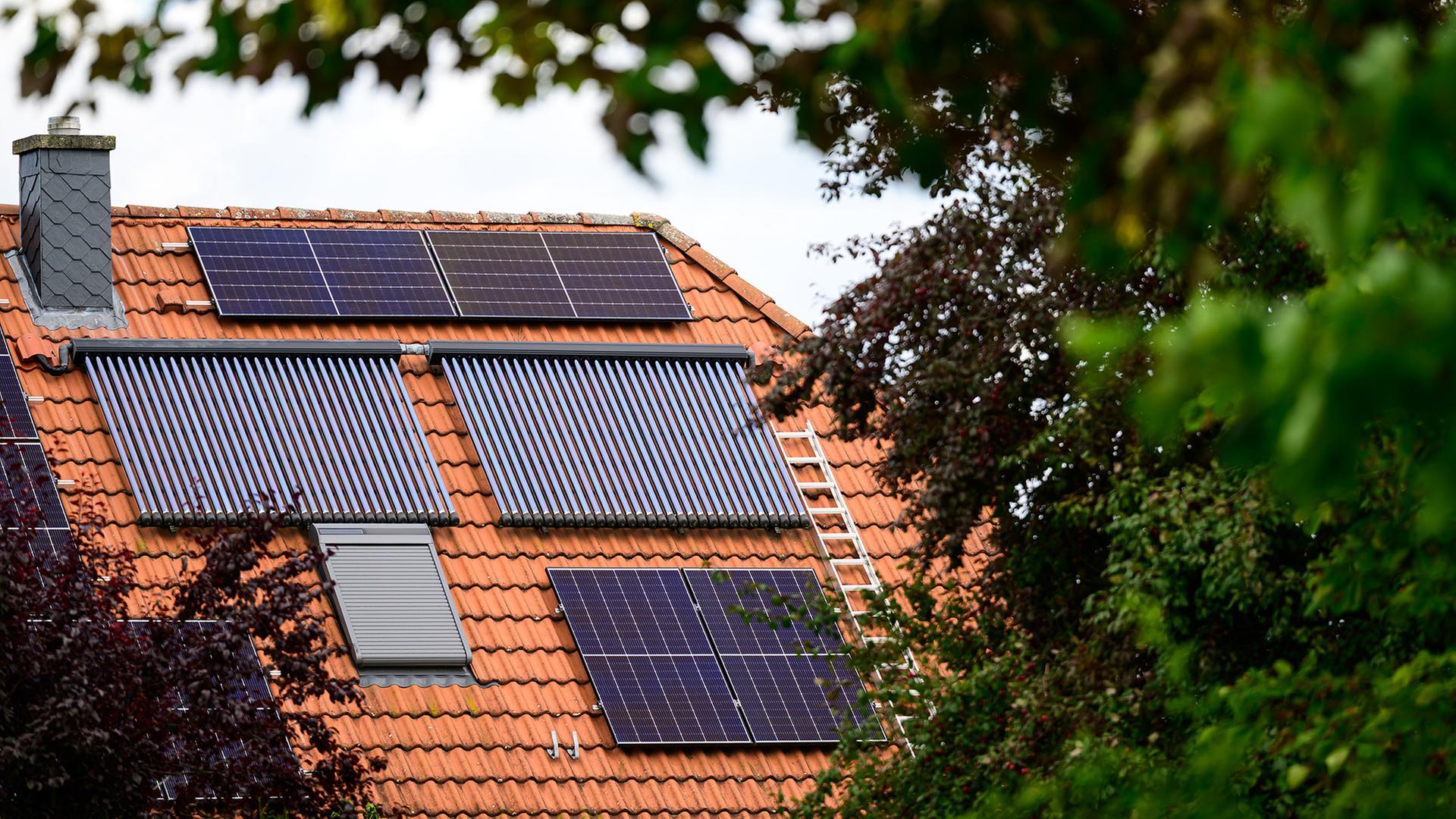 Solarmodule und Röhrenkollektoren sind auf einem Hausdach installiert. | dpa