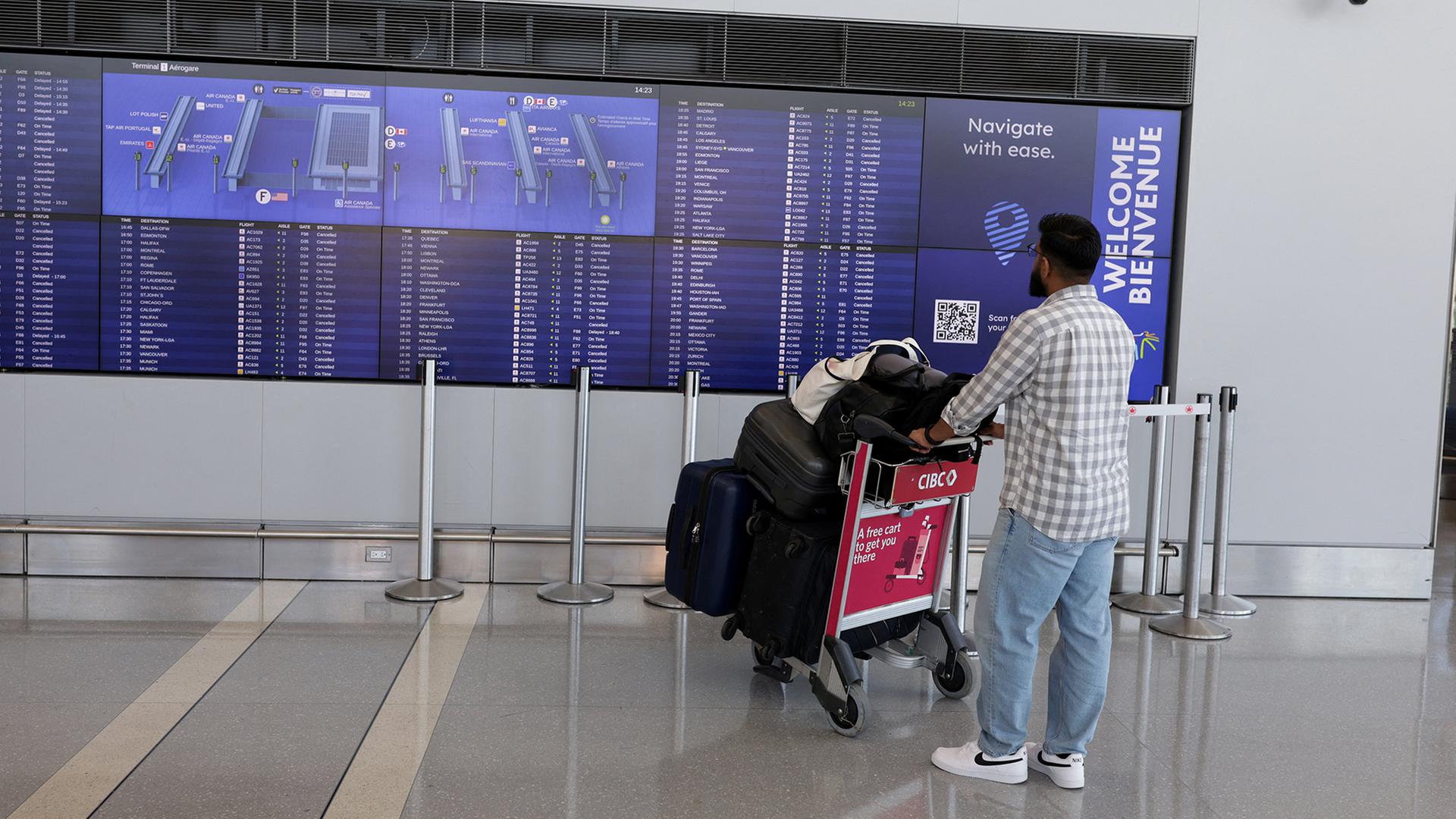 Ein Passagier schaut auf die Check-in-Anzeigetafel am Toronto Pearson International Airport in Mississauga. | REUTERS