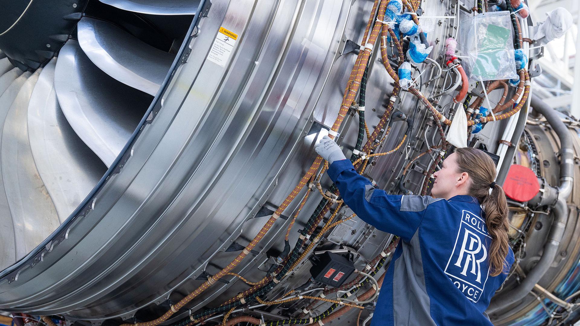 Eine Mitarbeiterin inspiziert im Rolls-Royce Werk Dahlewitz ein Triebwerk. | picture alliance/dpa