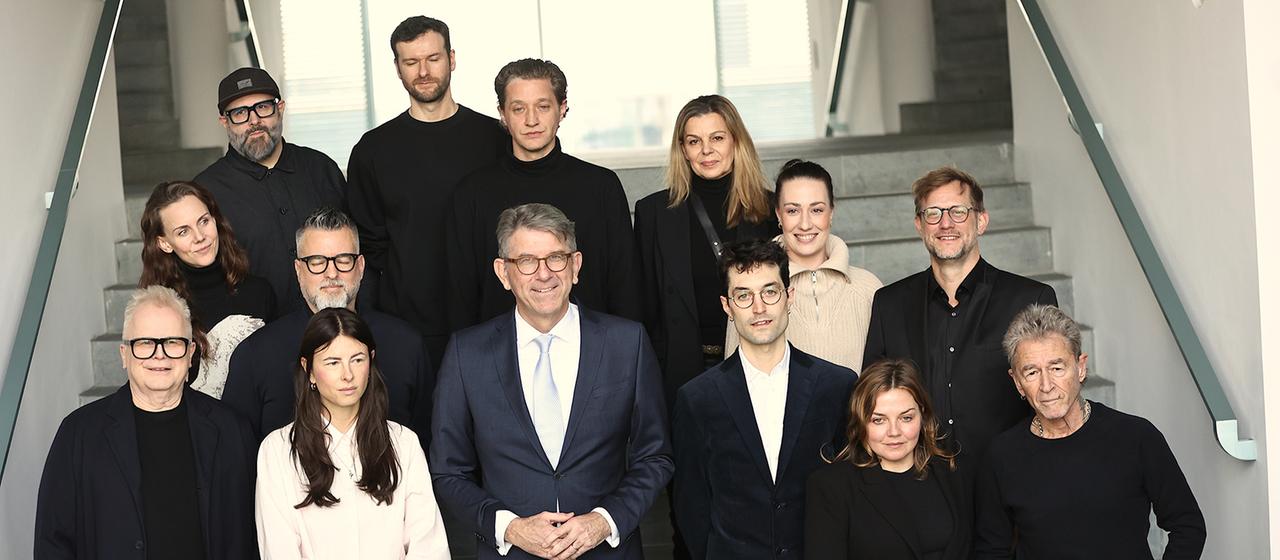 Wolfram Weimer steht mit Musikerinnen und Musikern zusammen auf einer Treppe.