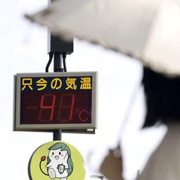 Eine Frau mit Sonnenschirm steht vor einem Thermometer, das 41° anzeigt