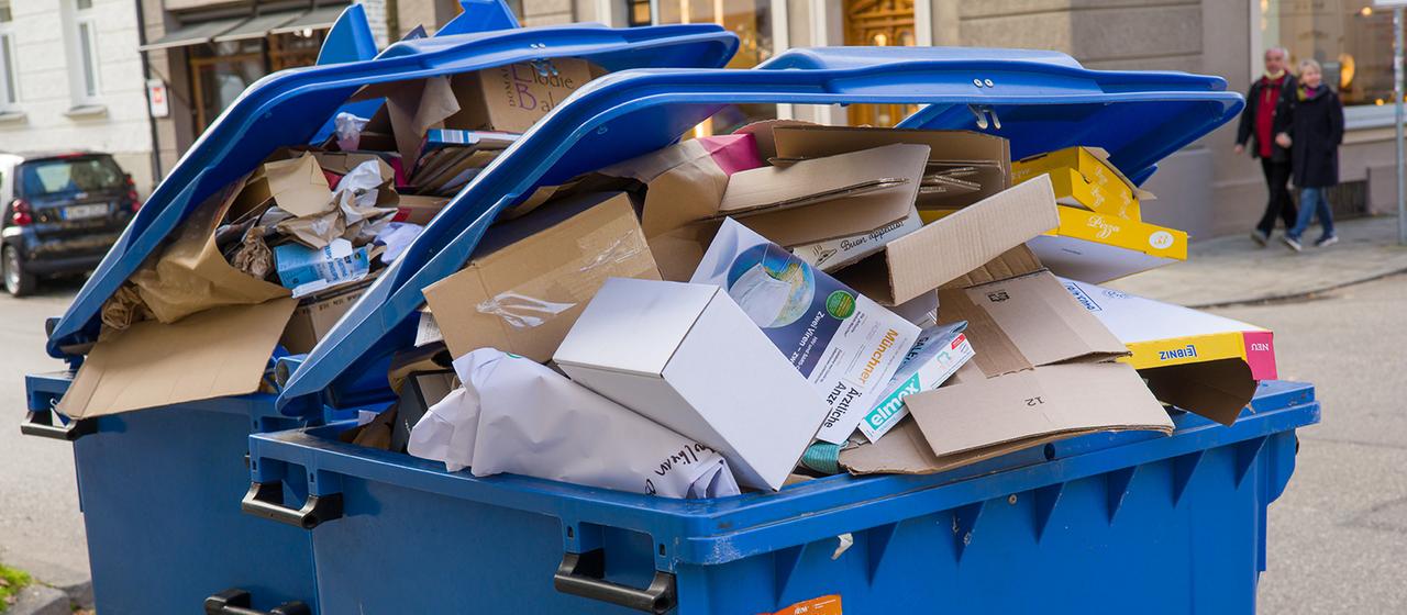 Übervolle Papiermülltonnen stehen zur Abholung bereit.
