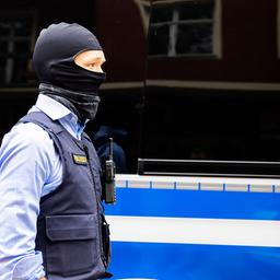 Symbolbild: Ein Polizist steht bei einer Hausdurchsuchung vor einem Fahrzeug. (Quelle: dpa/Christoph Soeder)