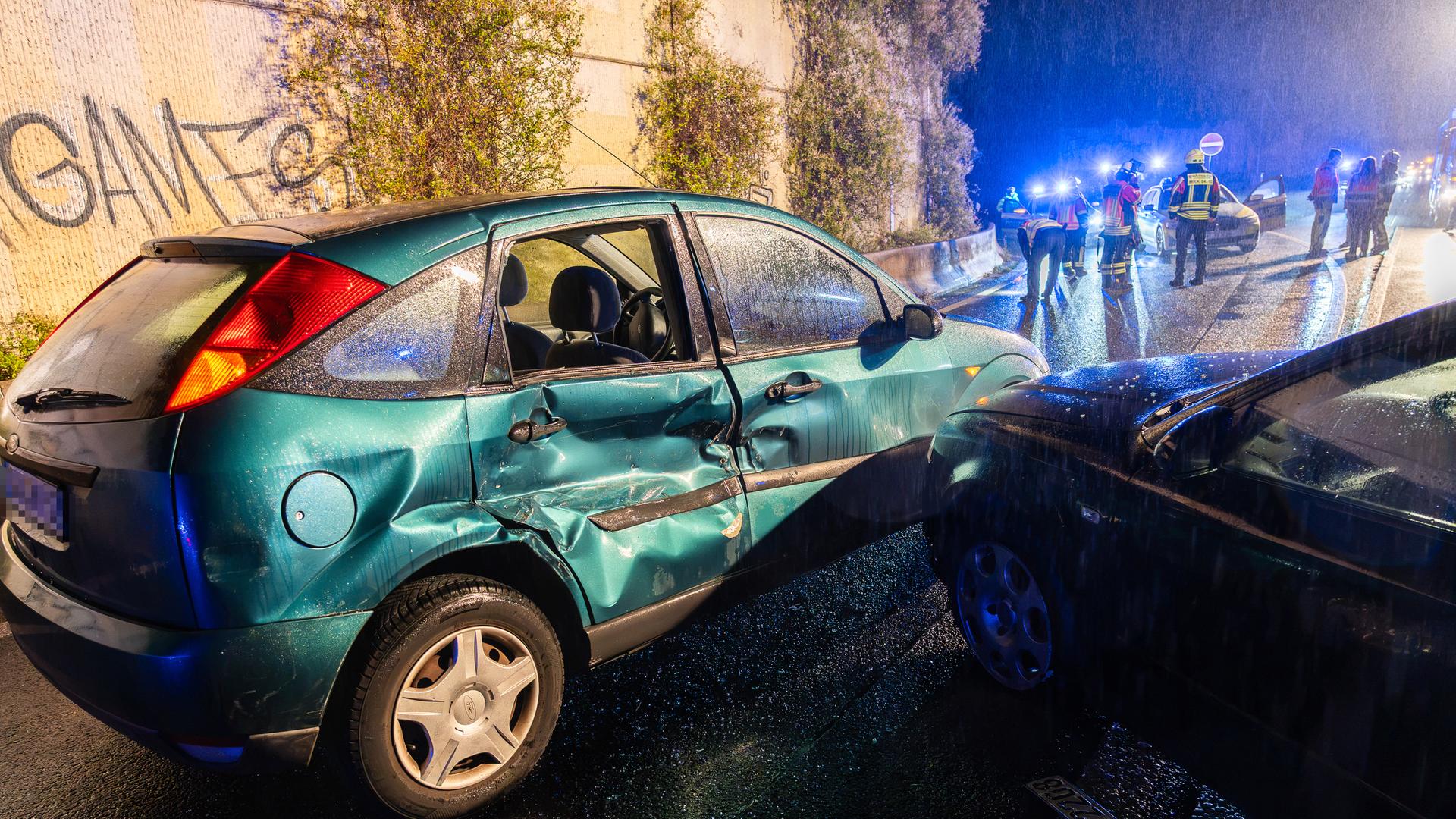 Zwei Auto stehen nach Unfall in Nähe von Betonmauer, im Hintergrund Einsatzkräfte | 5vision.news