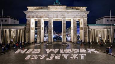 Kerzen formen den Satz "Nie wieder ist jetzt" vor dem Brandenburger Tor