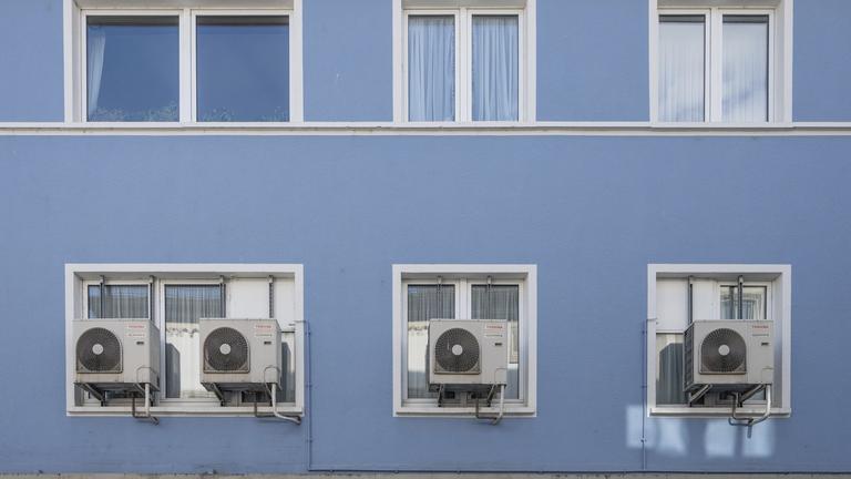 Klimaanlagen vor dem Fenster eines Mietshauses.