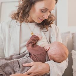 Eine Mutter stillt ihr Kind auf einem Sofa