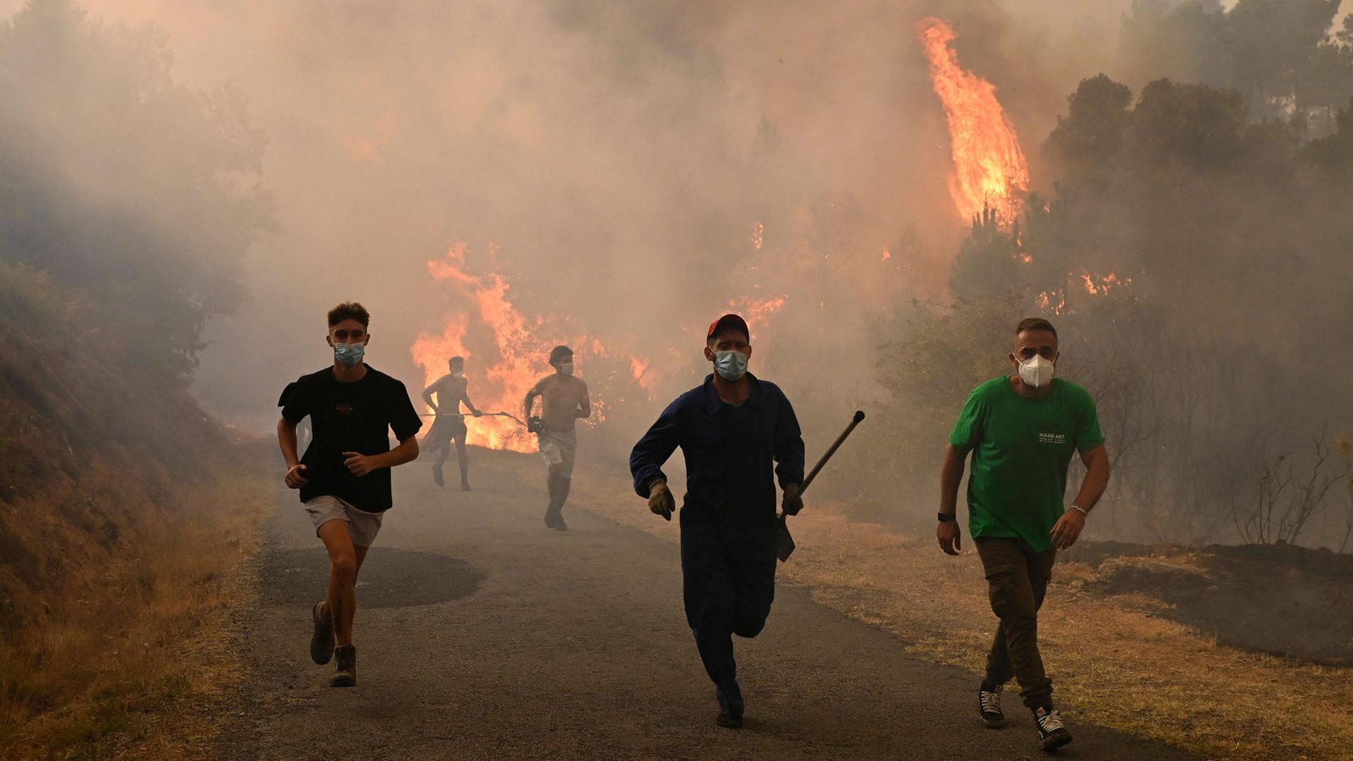 Menschen rennen vor einem Waldbrand in der Nähe des Dorfes Larouco im Nordwesten Spaniens. | AFP