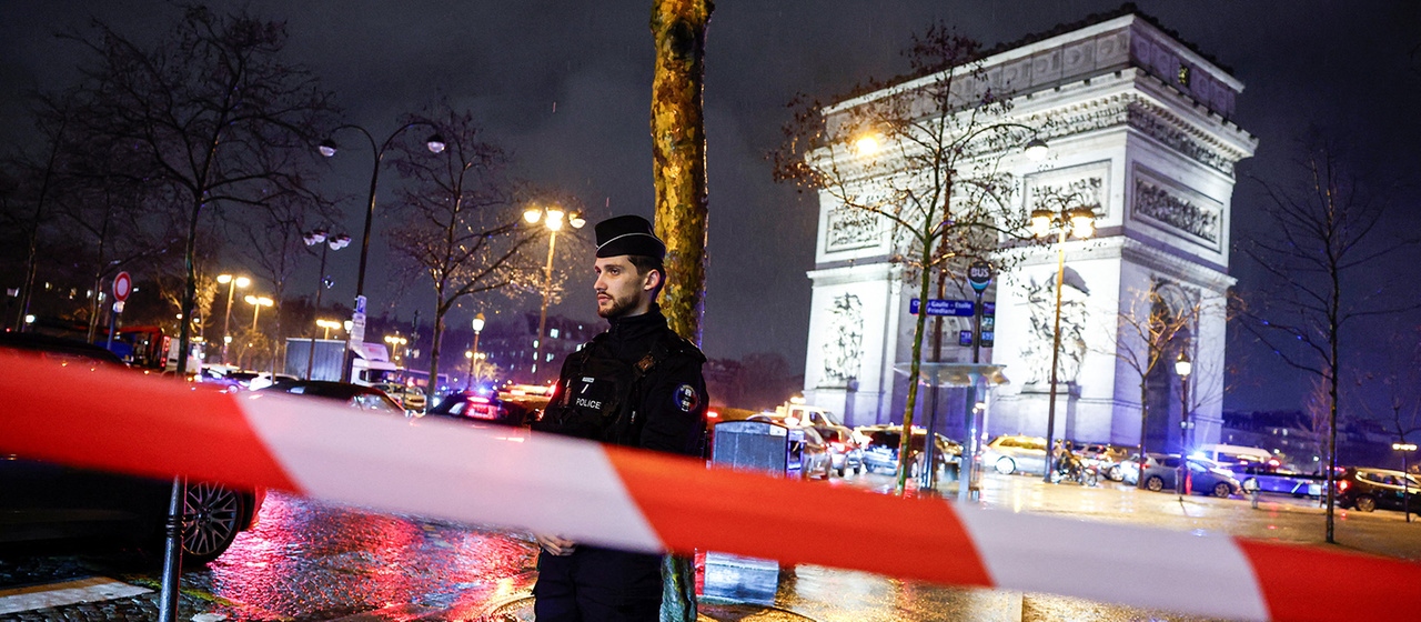 Ein Polizist steht vor dem Triumphbogen in Paris.
