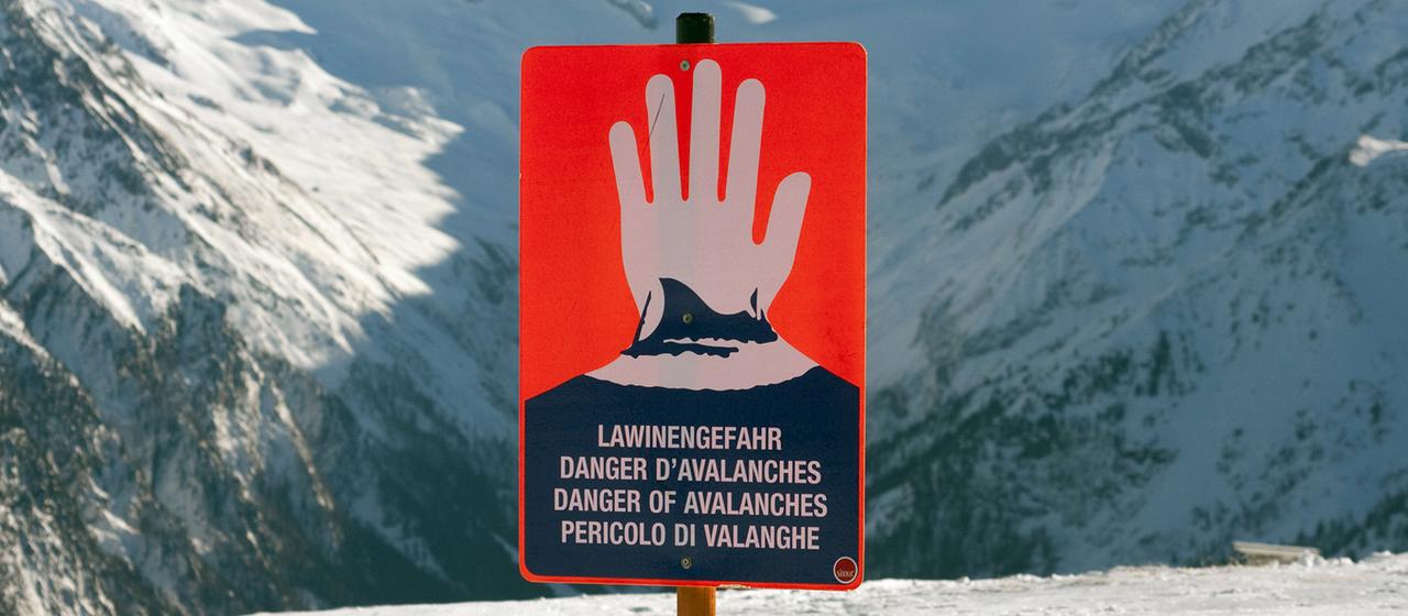 Ein Schild warnt in einem Skigebiet in den Alpen vor Lawinengefahr.