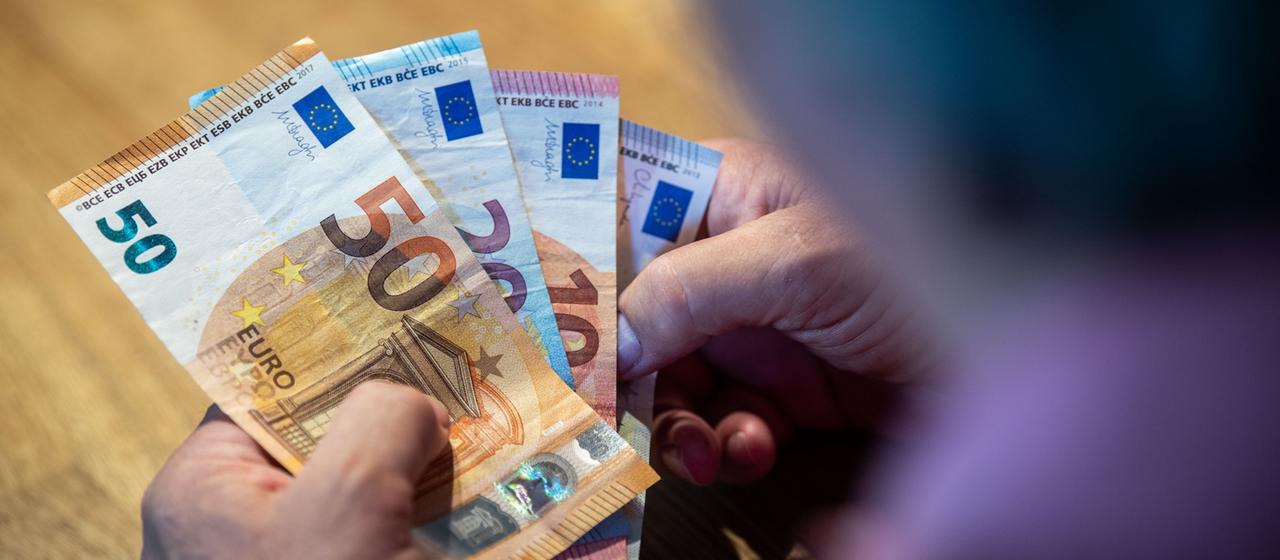 Ein älterer Mann sitzt an einem Tisch und zählt Geld.