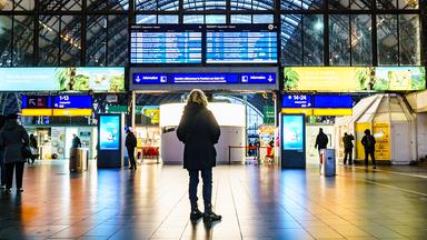 Eine Frau guckt auf eine Anzeigetafel im Frankfurter Hauptbahnhof.
