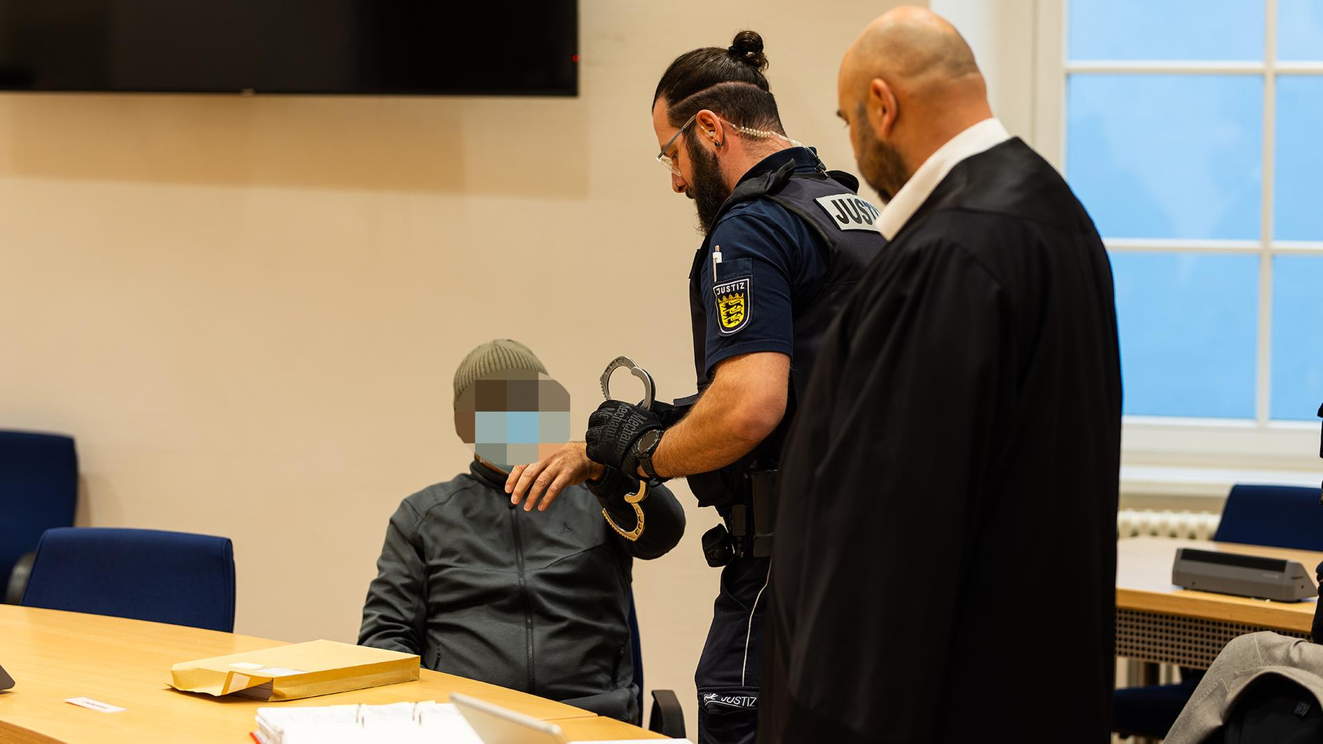 Ein Justizbeamter nimmt einem Angeklagten im Gerichtssaal in Waldshut-Tiengen (Baden-Württemberg) die Handschellen ab. | dpa