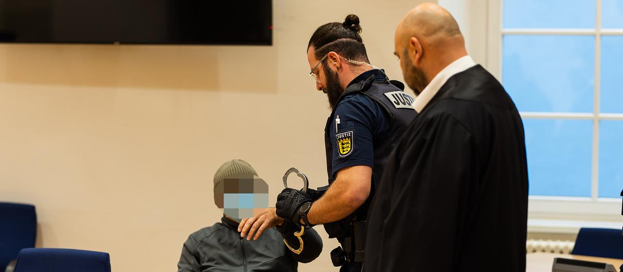 Ein Justizbeamter nimmt einem Angeklagten im Gerichtssaal in Waldshut-Tiengen (Baden-Württemberg) die Handschellen ab.
