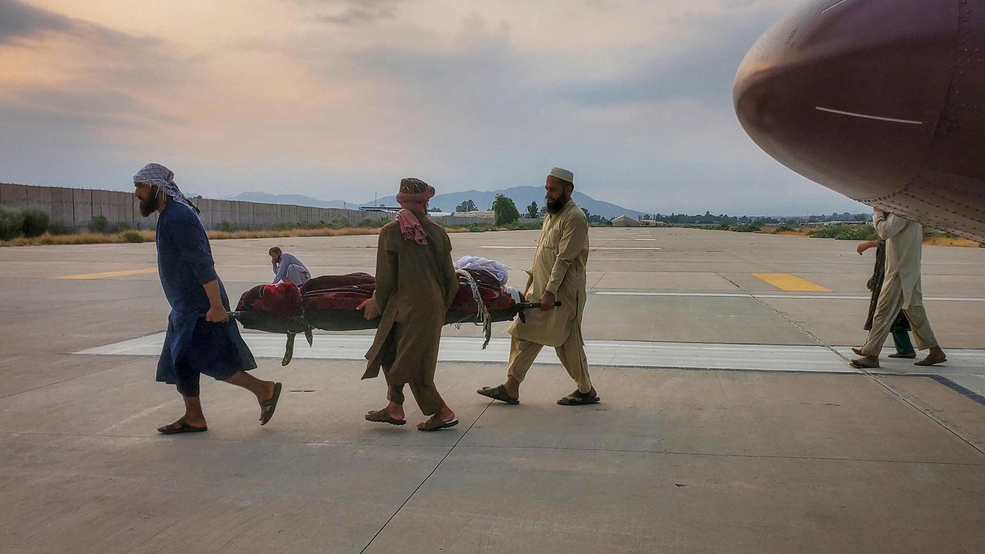 Menschen tragen ein Erdbebenopfer auf einer Trage zu einem Krankenwagen auf einem Flughafen in Jalalabad, Afghanistan. | REUTERS