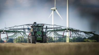 Traktor verteilt Gülle als Dünger auf einem Feld