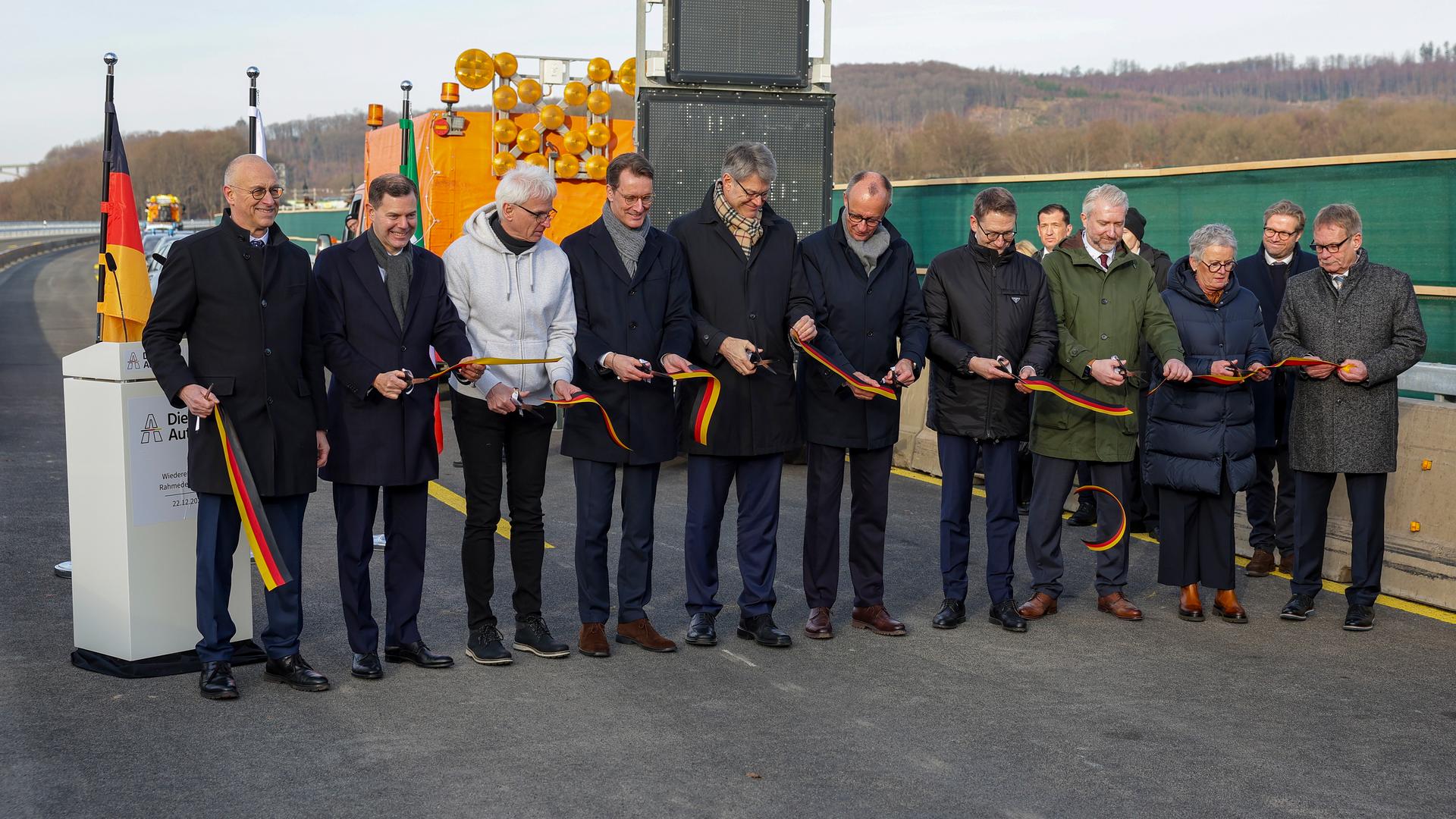 Henrik Wüst und Friedrich Merz durchschneiden das Band, um symbolisch die Rahmedetalbrücke wieder zu eröffnen  | EPA