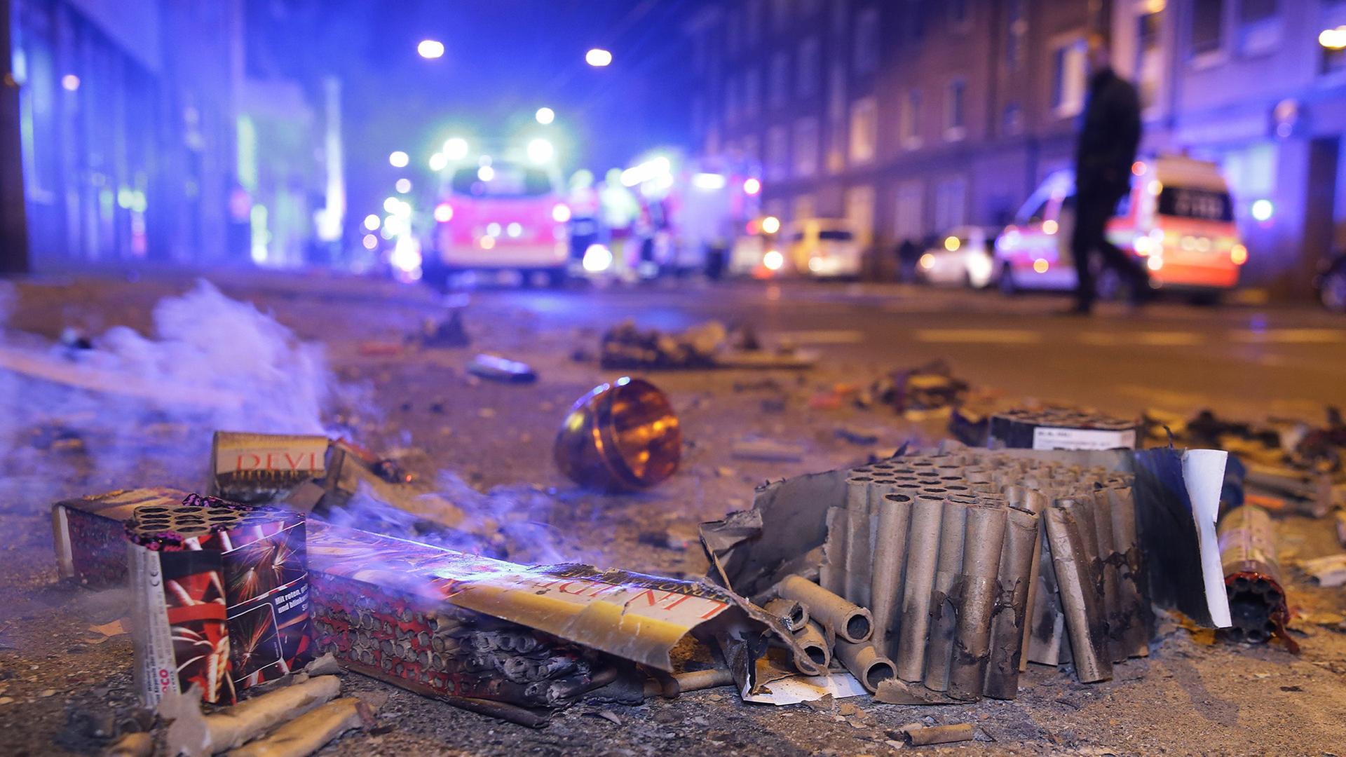 Abgebrannte Böller liegen nach der Silvesternacht auf der Straße im Hintergrund sind Feurwehrfahrzeuge zu sehen. | dpa