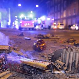 Abgebrannte Böller liegen nach der Silvesternacht auf der Straße im Hintergrund sind Feurwehrfahrzeuge zu sehen.