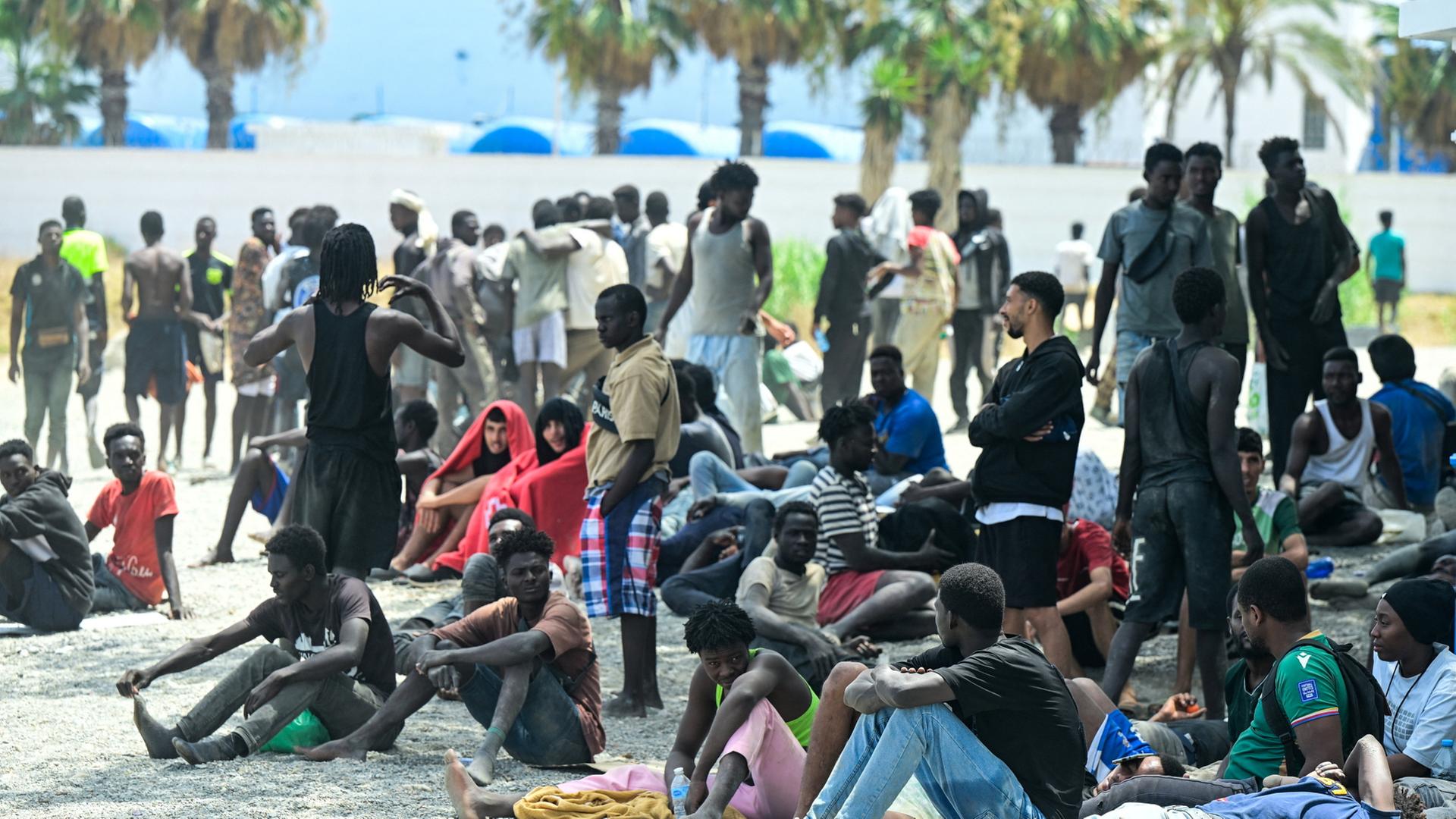 Menschen am Strand warten darauf, ein Center für Kurzzeit-Migration zu betreten. | REUTERS