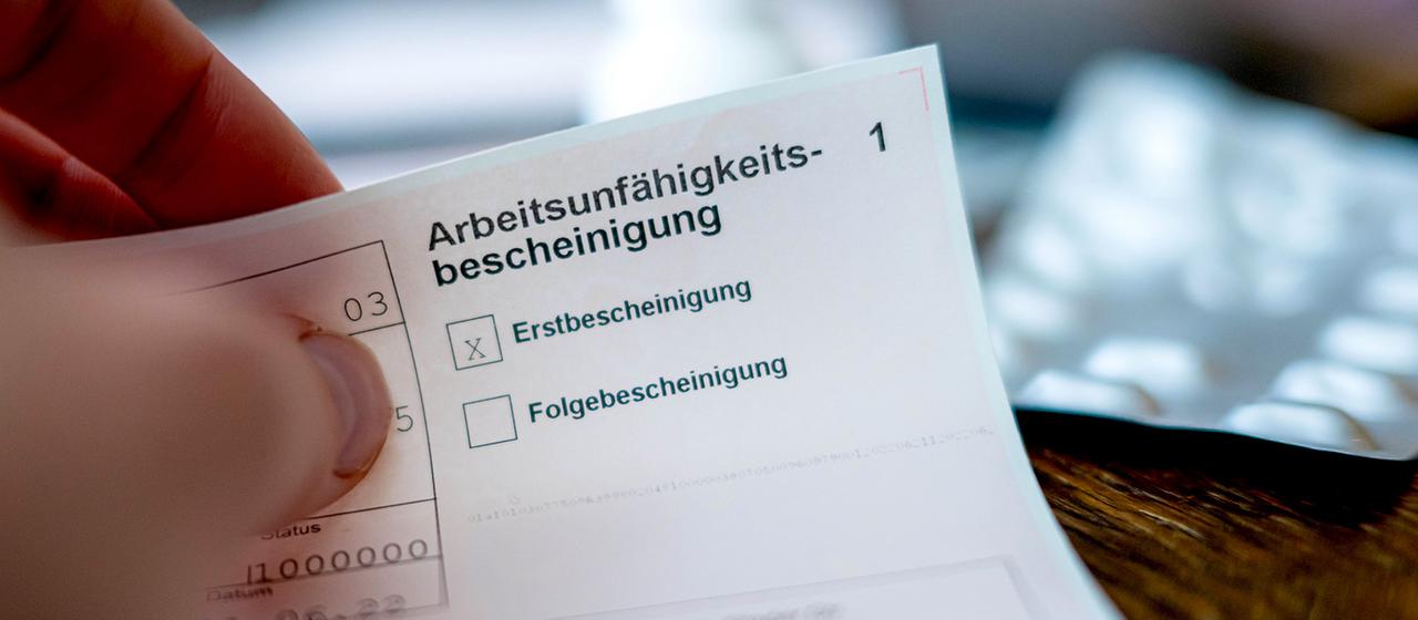 Eine Person hält eine ausgefüllte Arbeitsunfähigkeitsbescheinigung in der Hand.