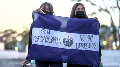Mitglieder einer feministischen Gruppe halten in El Salvador eine Fahne des Landes, auf der auf Spanisch zu lesen ist: "Ohne Demokratie gibt es keine Rechte"