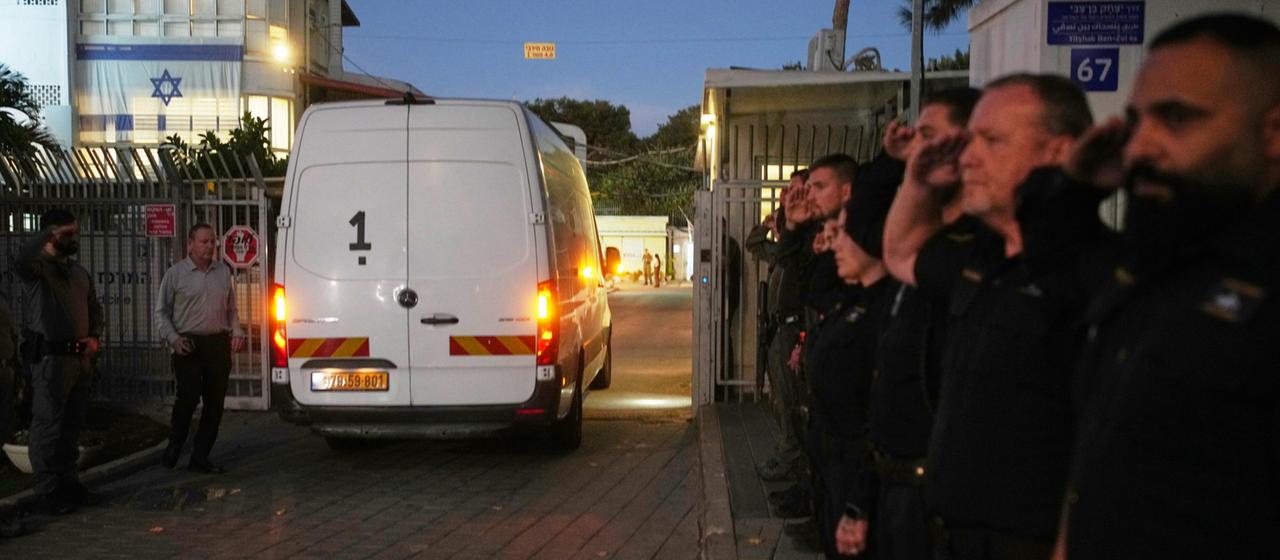 Ein Transporter fährt an Sicherheitskräften vorbei.