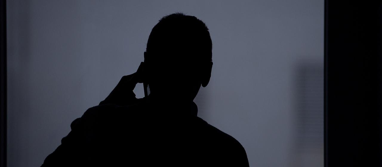 Die Silhouette eines Mannes, der mit einem Smartphone telefoniert.