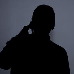 Die Silhouette eines Mannes, der mit einem Smartphone telefoniert.