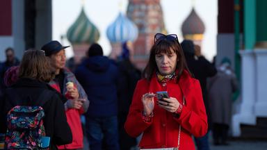 Eine Frau, die ihr Smartphone in der Hand hält, verlässt den Roten Platz in Moskau, Russland.