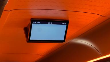 Eine Anzeigetafel in einem Zugabteil zeigt eine hellgraue Fläche, die einzigen Informationen sind Zugnummer, Abteilnummer und Uhrzeit