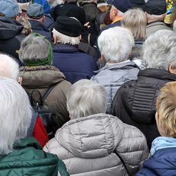 Senioren warten vor dem Eingang eines Messegeländes