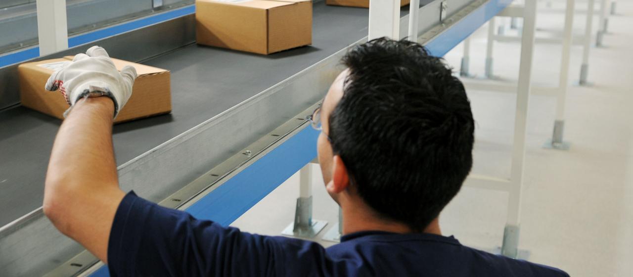 Ein Mann sortiert Pakete auf einem Fließband