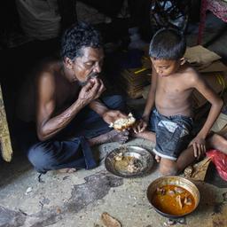Ein Vater und sein Sohn nehmen in ihrer Behausung in Colombo (Sri Lanka) eine Mahlzeit ein