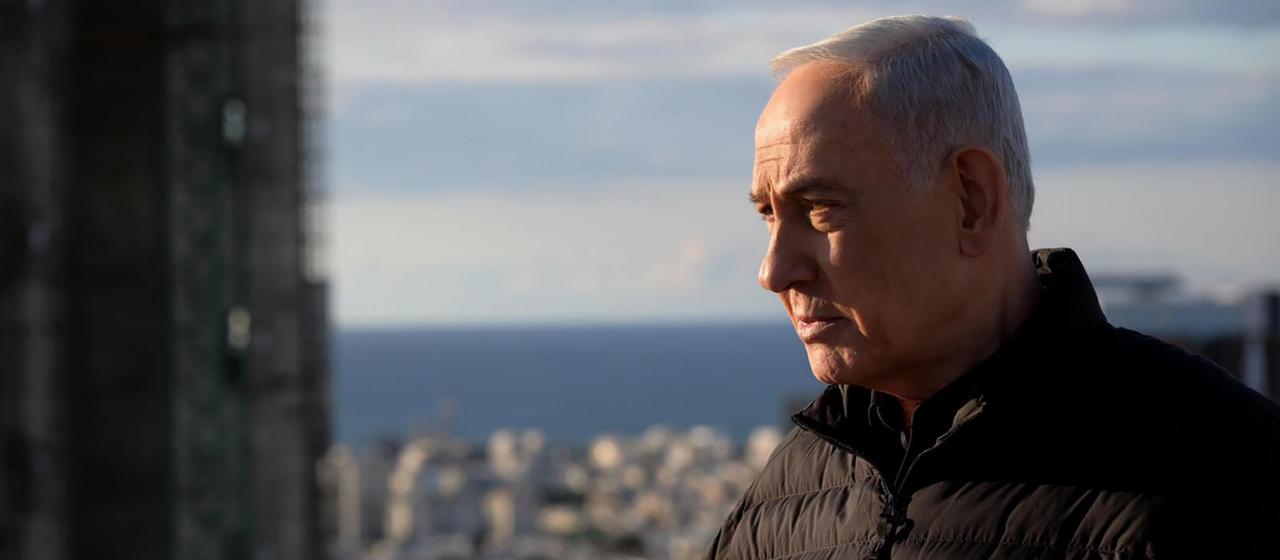 Benjamin Netanjahu steht auf einem hohen Gebäude, im Hintergrund das Meer.
