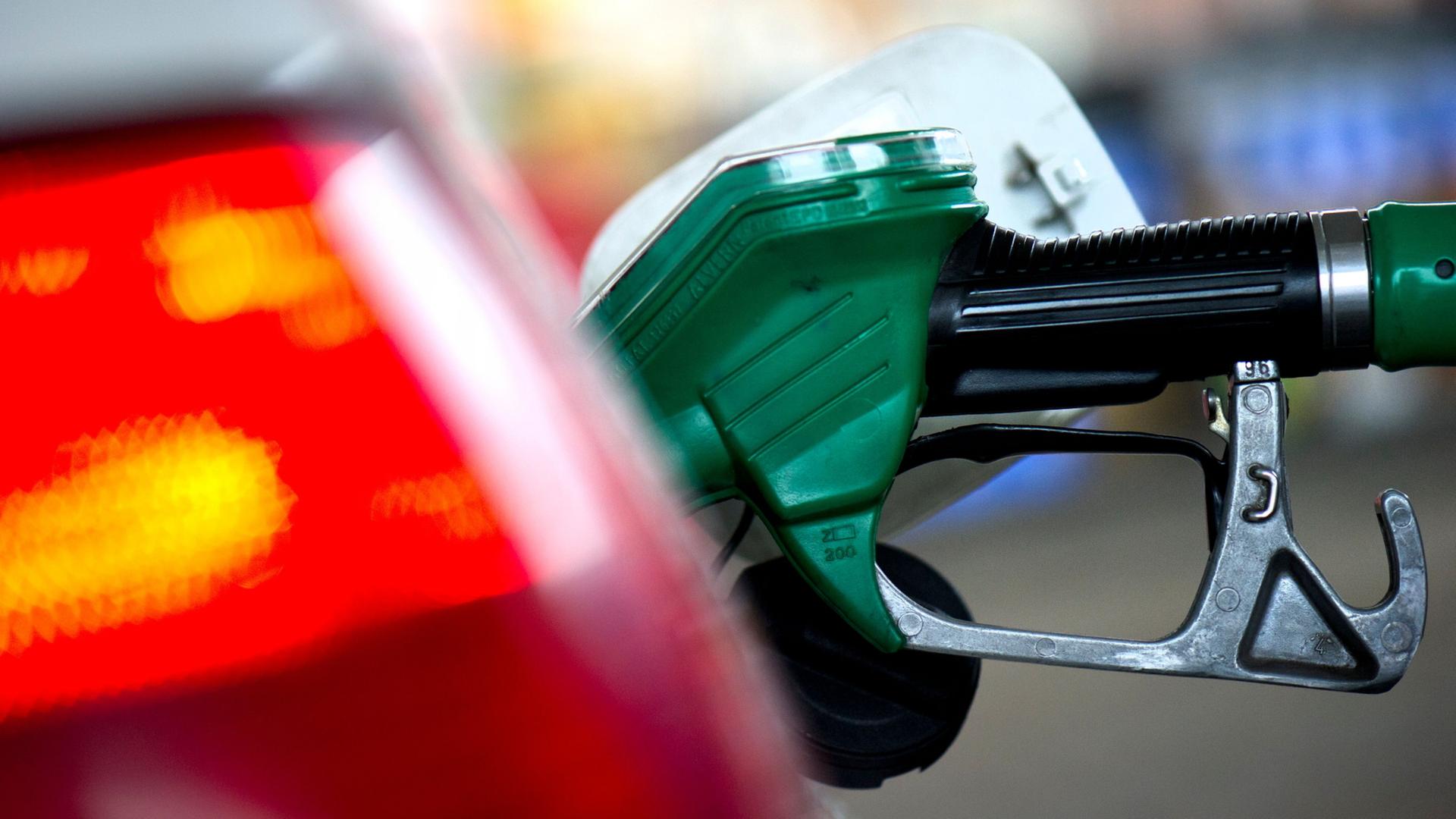An einer Tankstelle steckt ein Zapfstutzen einer Zapfsäule im Tank eines Autos. | Arno Burgi/dpa-Zentralbild/dpa