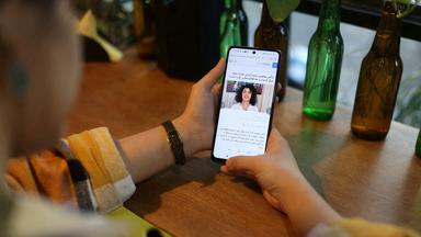 Eine Frau hält ein Smartphone, auf dem ein Bild von Narges Mohammadi zu sehen ist.
