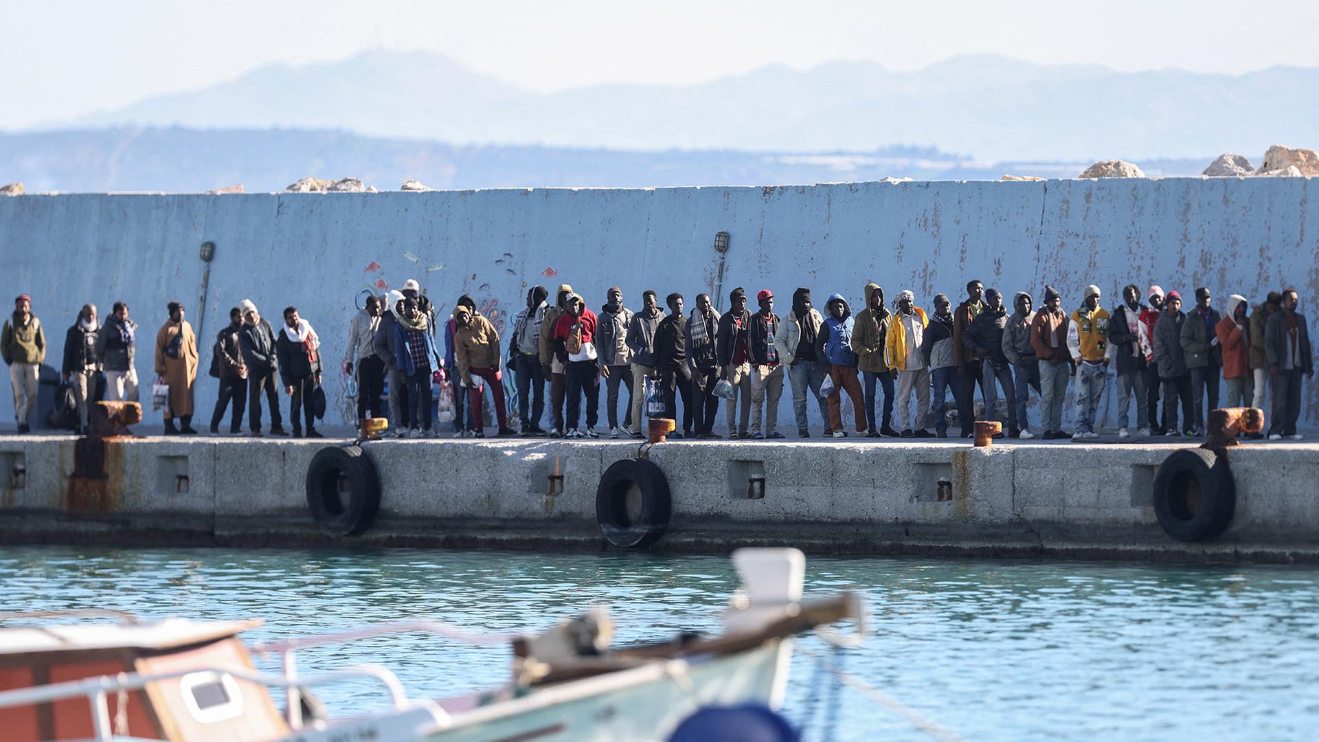 Geflüchtete Menschen stehen in einer Reihe am Hafen auf Kreta. | REUTERS