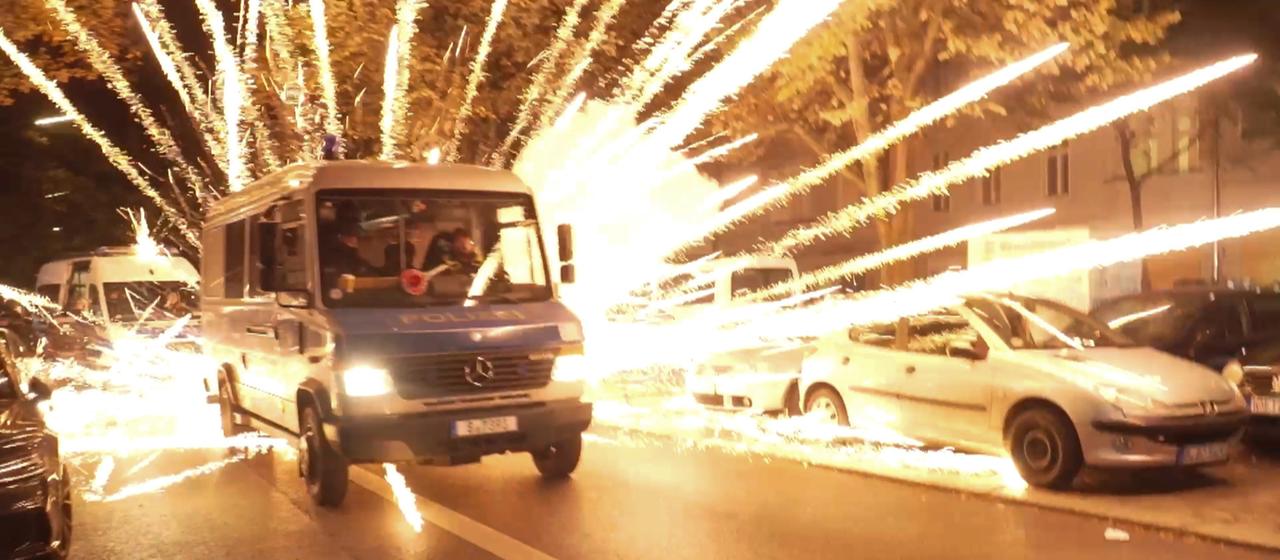 Feuerwerkskörper fliegen hinter einem Polizeiauto bei einer nicht angekündigten pro-palästinensischen Demonstration in Neukölln.