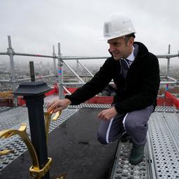 Emmanuel Macron berührt das Kreuz, das oben auf dem Turm der Kathedrale Notre Dame de Paris angebracht ist