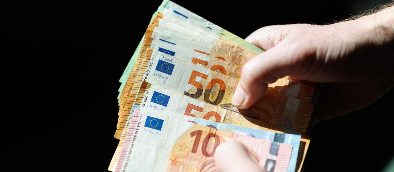 A man holds banknotes from his wallet in his hands.