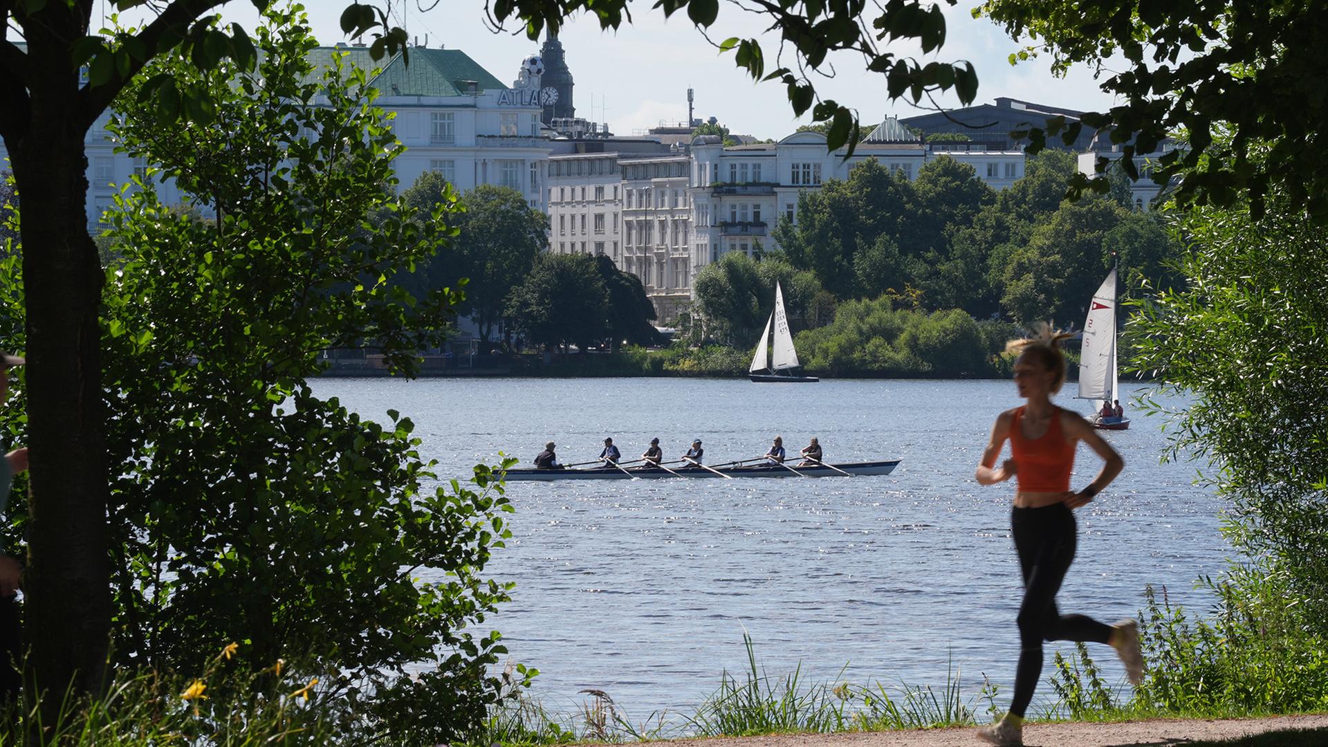 Eine Joggerin läuft am Ufer der Außenalster in Hamburg entlang. | dpa