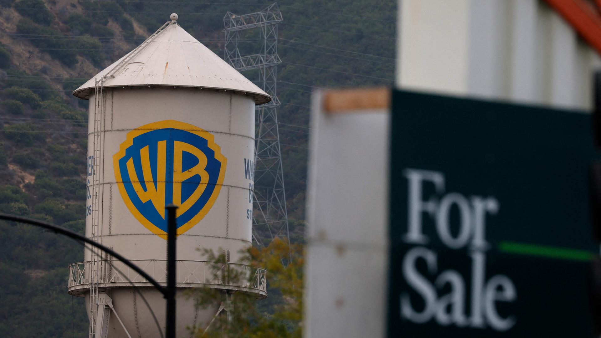 Das Warner-Brothers-Logo auf einem Wasserturm neben einem For-Sale-Schild in Burbank, USA | Getty Images via AFP