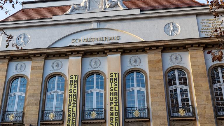  Frontalaufnahme der oberen Außenansicht des Staatsschauspiels Dresden mit dekorativen Schriftzügen und Skulpturen.