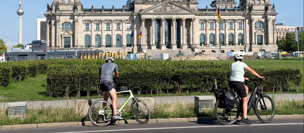 Zwei Fahrradfahrer halten vor dem Reichstagsgebäude, um ein Foto zu machen.
