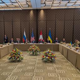 Die Flaggen Russlands, der USA, der Schweiz und der Ukraine hinter einem Verhandlungstisch in Genf