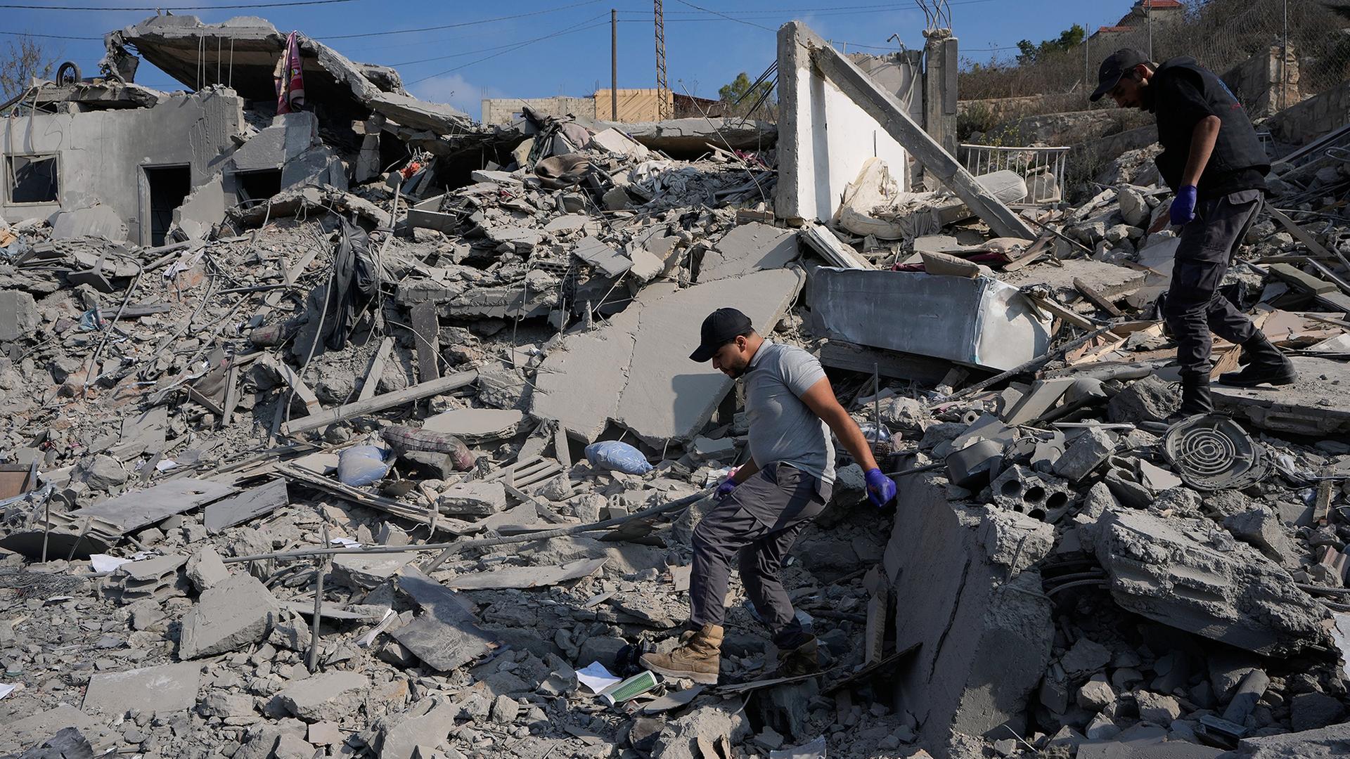 Menschen suchen in den Trümmern eines zerstörten Gebäudes. | Mohammed Zaatari/AP/dpa